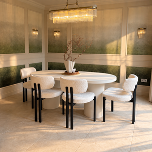 Oval white micro cement dining table with four black bouclé chairs