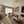 Round ceramic coffee table with white top and walnut legs beside upholstered sofas