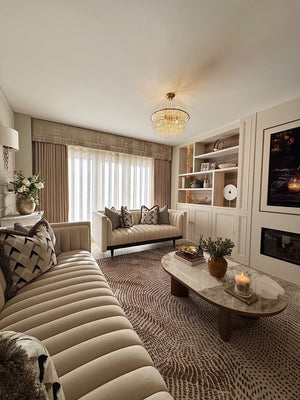 Round ceramic coffee table with white top and walnut legs beside upholstered sofas