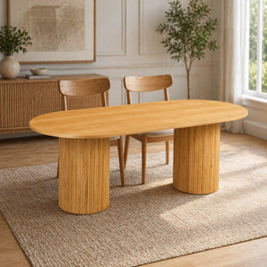 Wooden dining table with two chairs in a room with a rug and plants.