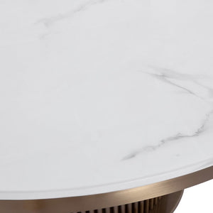 Close-up of a round white marble tabletop with soft gray veining and a brushed brass or bronze metal base edge visible along the curved rim.