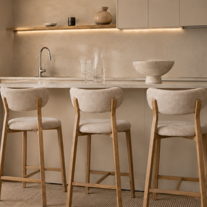 Set of upholstered barstools with beige fabric seats, rounded backs, and oak legs