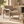 Brown textured armchair with a cushioned seat, rounded back, and polished metal arms