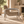 Brown armchair with textured upholstery and a curved chrome frame, in side profile