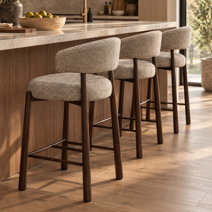 Upholstered barstool with beige fabric seat and rounded back, dark wood legs, footrest.