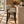 Barstool with light gray upholstered seat, rounded backrest, black four-leg base.