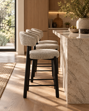 Barstool with light gray upholstered seat, rounded backrest, black four-leg base.
