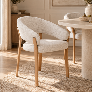 Light beige dining chair with curved back, wooden armrests, and tapered legs