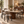 Gray upholstered dining chair with curved arms and black legs around a table