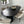 A modern dark wood oval dining table with a fluted pedestal base, surrounded by six cream upholstered dining chairs with black legs, set in a contemporary dining room with light gray tiled flooring.