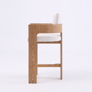 A modern wooden bar stool with a light oak frame and a white upholstered seat and backrest, shown from the side against a plain white background.