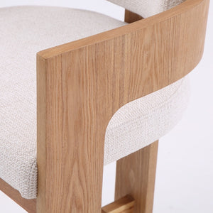 Close-up of a modern wooden chair with a light beige textured fabric seat and a natural oak wood frame, set against a plain white background.