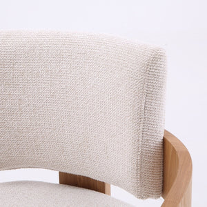 Close-up of a chair back cushion upholstered in a textured cream bouclé fabric, mounted on a light natural wood frame against a white background.