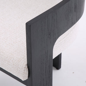 Close-up of a modern upholstered chair or bench corner, showing a light beige textured fabric seat with a dark charcoal wood frame on a white background.