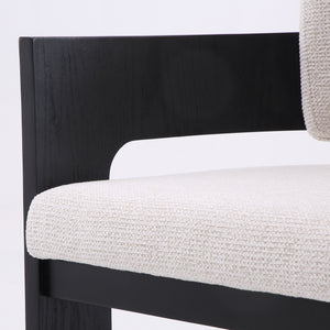 Close-up of a modern chair showing a black wooden frame with textured off-white woven upholstery on the seat and backrest.