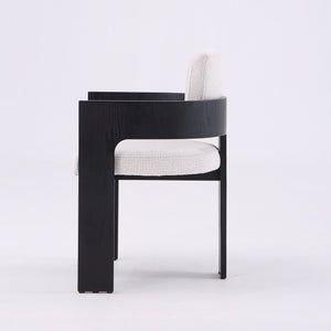 A modern armchair with a thick black wooden frame and light beige textured fabric seat and back cushions, shown from a side profile against a plain white studio background.