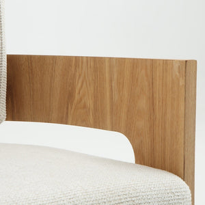 Close-up of a modern armchair corner showing a light beige textured fabric seat and back, a curved white inner arm, and a natural oak wood backrest panel on a white background.