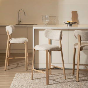 Beige-upholstered oak barstool with curved back and angled wood legs in kitchen