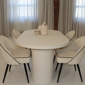 White dining table with six matching chairs in a room with light-colored curtains.