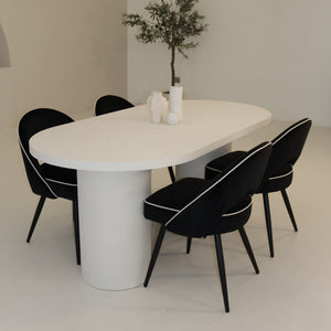 Modern dining room with a white oval table and black chairs.