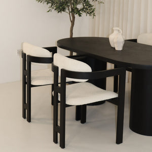 Black micro cement dining table with two white bouclé chairs