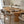 A round wooden dining table with a slatted pedestal base, surrounded by upholstered dining chairs in a bright, modern dining room setting.