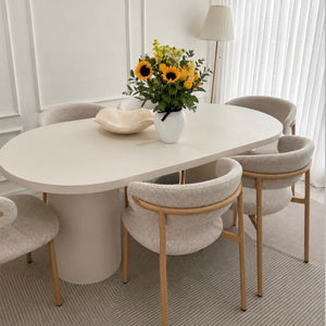 Modern dining room with a white oval table and chairs, featuring a vase of sunflowers.