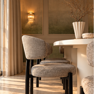 Gray upholstered dining chair with black legs beside a white oval table