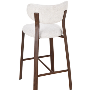 Side view of a light upholstered barstool with walnut wood legs and diagonal brace