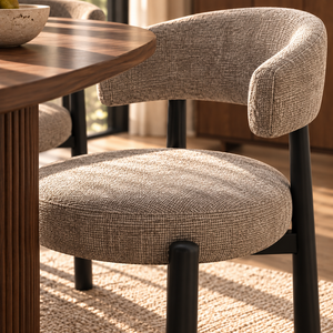 Gray upholstered dining chair seat and curved armrest with black legs close-up
