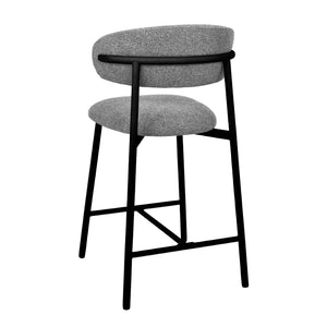 A modern counter-height bar stool with a textured gray fabric seat and backrest cushion, supported by a slim black metal frame with a footrest.