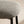 Close-up of a modern stool with a textured gray and white woven fabric seat cushion and slim black metal legs, set against a warm beige background.