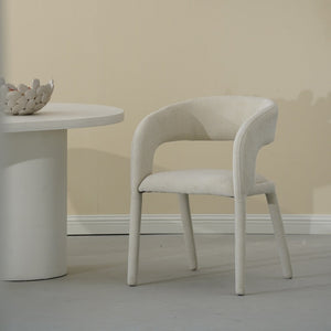 White chair and round table against a beige wall