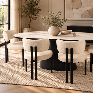Black ceramic dining table with four cream bouclé chairs