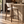 Walnut barstool with curved back and light beige upholstery, angled legs and foot rail
