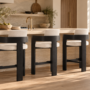 Multiple black wood barstools with cream upholstered seats