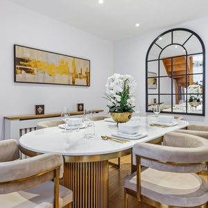 Modern dining room with round table, chairs, and decorative elements.