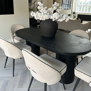 Modern dining room with a black oval table and white chairs.
