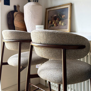 Three round stools in a room with wooden shelves and decorative items.