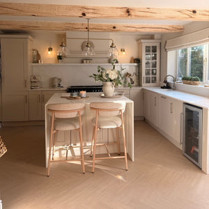 Small kitchen with white cabinets, a refrigerator, and a dining area with chairs.