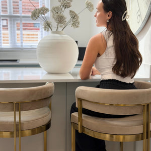Woman sitting at a kitchen counter with decorative elements in the background