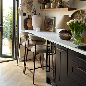 Modern kitchen with wooden shelves, bar stools, and a window view.