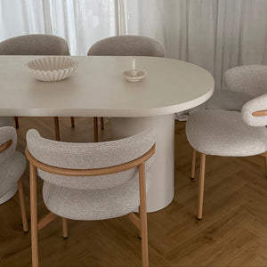 Dining area with a white round table and gray chairs in a room with light curtains.