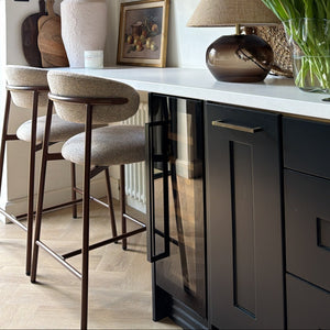 Modern kitchen with bar stools, shelves, and decorative items.