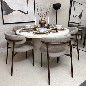 Modern dining room with a round table and chairs, featuring abstract art on the walls.