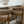 White vase on a table with two beige chairs and a clock in the background