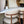 Decorative setup with a vase, candle, and chairs on a shelf.