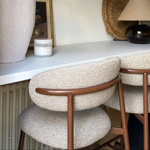 Decorative setup with a vase, candle, and chairs on a shelf.