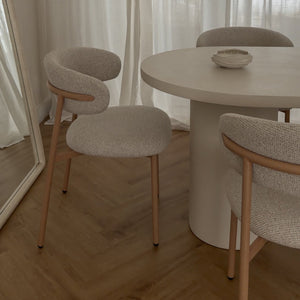 Dining area with a round table and chairs in front of sheer curtains.