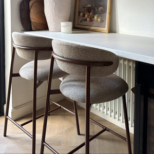 Modern kitchen with bar stools, white countertop, and wooden shelves with decorative items.